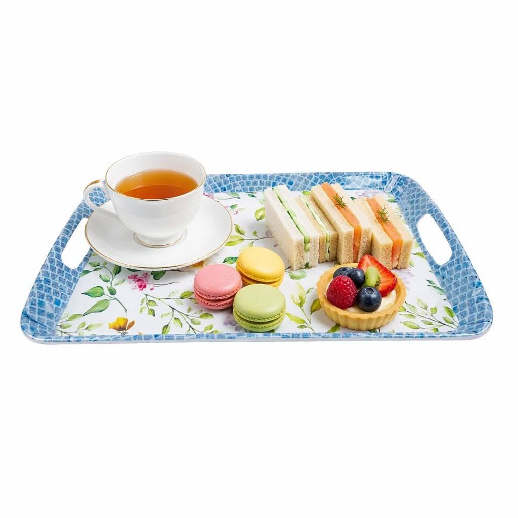 Elegant blue floral print melamine serving tray with handles, showcasing a British afternoon tea setup with a white teacup, finger sandwiches, and macarons.